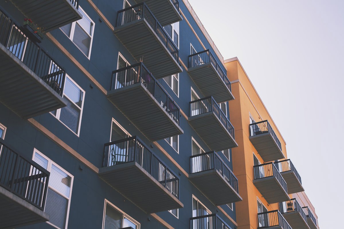 Fachada de prédio residencial com várias janelas e varandas em dia ensolarado