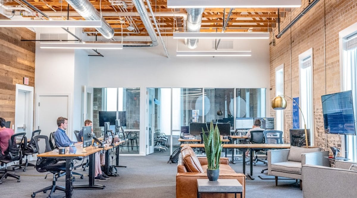 Espaço de coworking profissional com mesas de trabalho, iluminação adequada e estrutura regulamentada