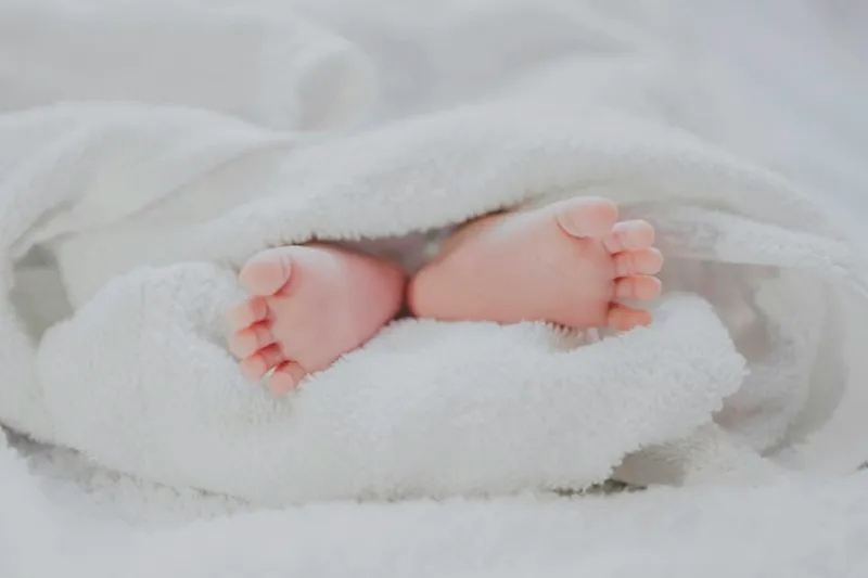 Pés de bebê Pezinhos de um bebê recém-nascido cobertos por uma manta branca e macia