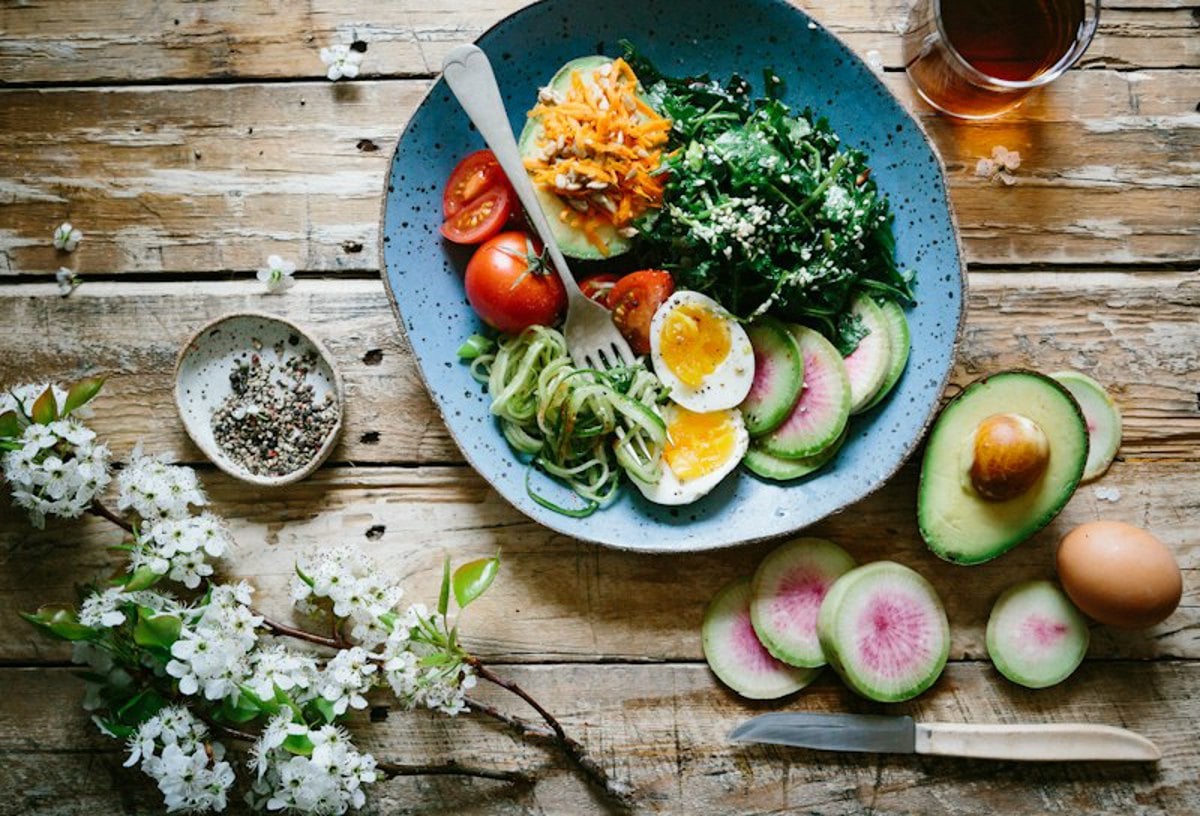 Ingredientes frescos como vegetais e ovos dispostos em uma mesa de madeira