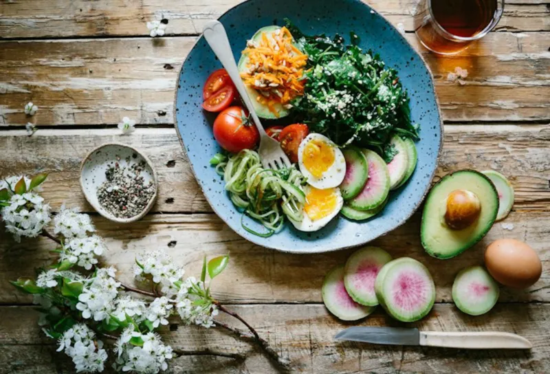 Ingredientes frescos como vegetais e ovos dispostos em uma mesa de madeira