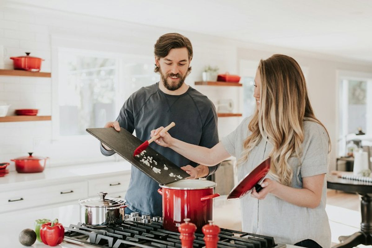 Duas pessoas cozinhando juntas em uma cozinha clara