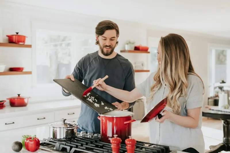 Duas pessoas cozinhando juntas em uma cozinha clara