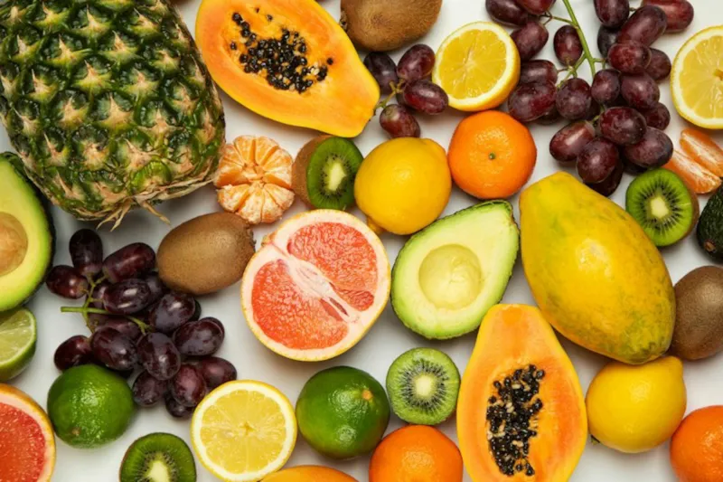 Mesa com frutas variadas como mamão, abacate e laranja