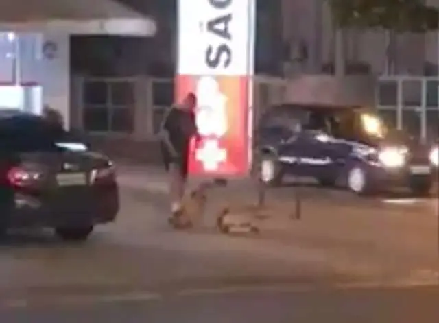Homem pisa em cães para mantê-los sentados na frente de farmácia.